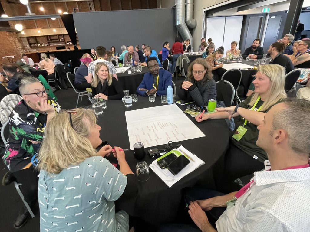 IZE members sitting at round tables during a discussion at the 2024 IZE Conference